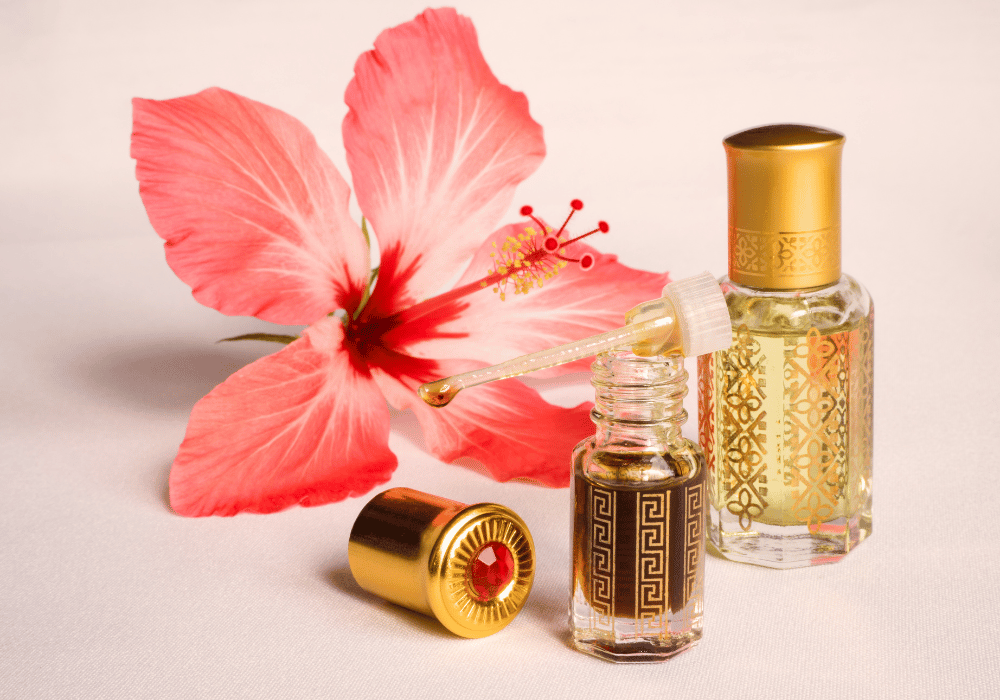Zwei kleine Fläschchen mit orientalischem Duftöl neben einer rosa Blüte