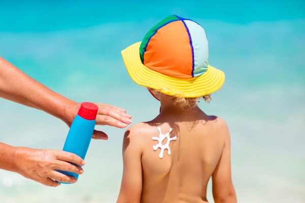 Kind mit Sonnencreme am Strand
